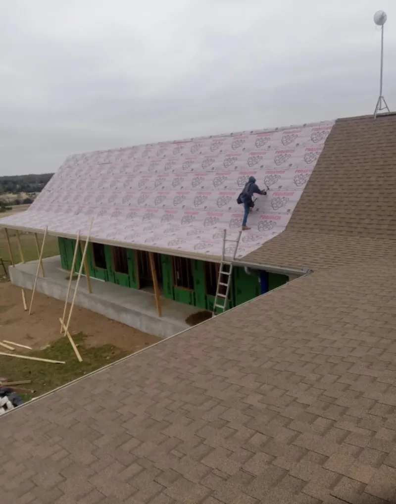 Worker preparing underlayment for a metal roof installation in Struthers